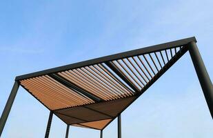 Wooden slats roof with blue sky background. Wooden slat shading structure. photo