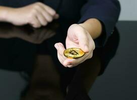 Cerca de la empresaria sosteniendo algunas piezas de token bitcoin dorado foto