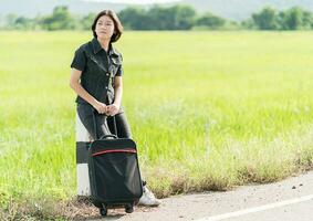 Woman with luggage hitchhiking along a road photo