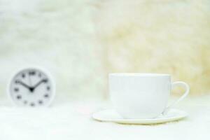 Cup of coffee with alarm clock on table photo