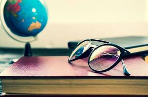 Eye glasses and books beside the window photo