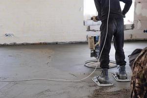 embestida y molienda de semi seco piso maestra por un máquina con un giratorio disco para arrasamiento. construcción de un hormigón piso en el casa, un Maestro con especial equipo. foto