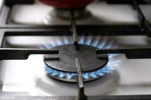 Ignition of the gas burner on the stove in the kitchen. Use of natural resources, economy, cooking on fire. Close-up photo