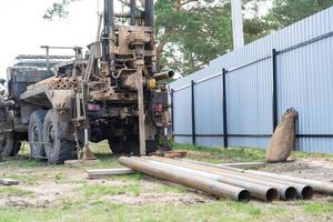 Drilling rig on zil car are drilling artesian well for water in ground. Insertion of metal casing pipe into ground, installation of individual drinking supply photo