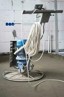 Ramming and grinding of semi-dry floor screed by a machine with a rotating disk for leveling. Construction of a concrete floor in the house, a master with special equipment. photo