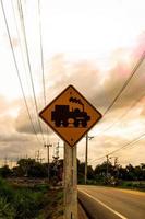 Traffic sign, watch out for the train. Drive slowly and watch out for the way ahead. There is a train passing by on rural roads of Thailand and the beautiful blue sky in the countryside. photo