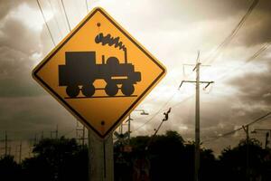 Traffic sign, watch out for the train. Drive slowly and watch out for the way ahead. There is a train passing by on rural roads of Thailand and the beautiful blue sky in the countryside. photo