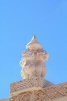The beautiful and delicate Thai sculpture of white kirin in stucco on the church wall is a beautiful landmark and tourist attraction and against the Thai temple church wall and blue sky background. photo