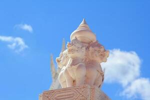 The beautiful and delicate Thai sculpture of white kirin in stucco on the church wall is a beautiful landmark and tourist attraction and against the Thai temple church wall and blue sky background. photo