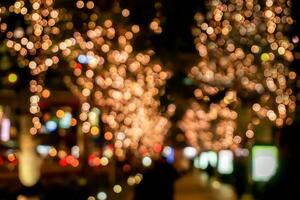 Blurred and bokeh of LED refection lighting decorate on trees with city night life in Osaka, Japan. photo