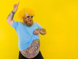 Fat man with wig in head and sunglasses dances photo