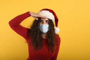 Woman with face mask look far for something. yellow background photo