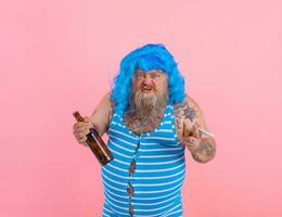 Fat man with beard and wig smokes cigarettes and drinks beer photo