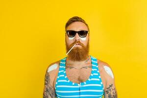 man with tattoos and swimsuit puts on sunscreen photo