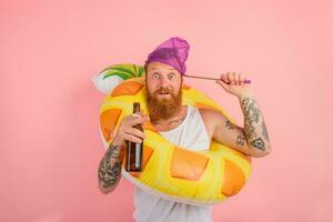 asombrado hombre es Listo a nadar con un rosquilla salvador de la vida con cerveza y cigarrillo en mano foto