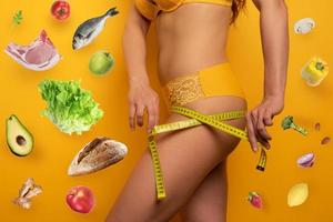 Girl measures with the meter the diet results. yellow background photo