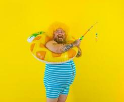 Fat happy man with wig in head plays with the fishing rod photo