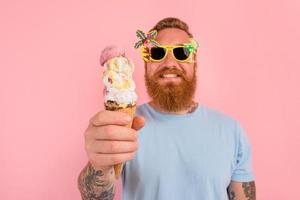 Happy man with beard and tattoos eats a big icecream photo