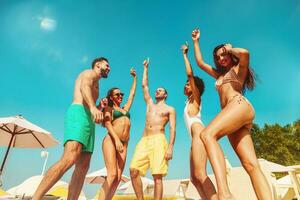 Group of friends in swimsuit dance music in a swimming pool photo