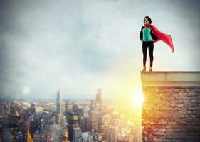 Successful businesswoman acts like a super hero above the roof of a building. Concept of determination and success photo