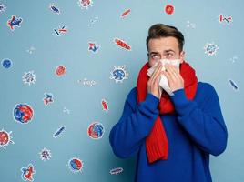 Boy caught a cold and is surrounded by viruses and bacteria. Studio on Cyan background photo