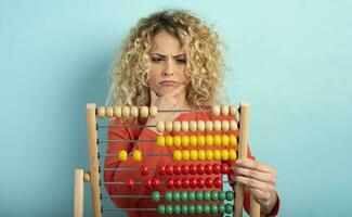 Girl with abacus is confused about the sum . cyan background photo