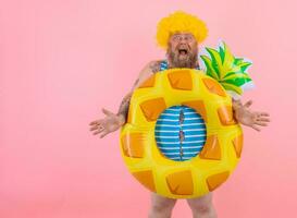 Fat amazed man with wig in head is ready to swim with a donut lifesaver photo