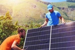 Workers assemble energy system with solar panel for electricity and hot water photo