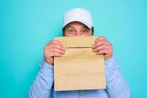 Delivery man hides his face with a food package photo