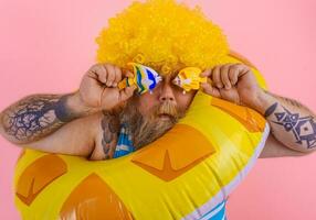 Fat man with wig in head is ready to swim with a donut lifesaver photo