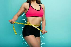 Determinated Sport woman has an excellent physical shape and measure with the meter. Cyan background photo