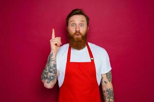 amazed isolated chef with beard and red apron photo