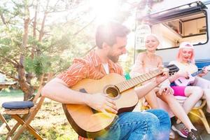 amigos tener un picnic con un camper y jugar con guitarra foto