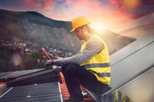 Man works on renewable energy system with solar panel for electricity and hot water photo