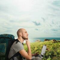 Explorer plans a new travel to a tropical beach with his laptop photo
