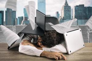 cansado empresario dormido debajo un pila de laptops debido a carga de trabajo foto