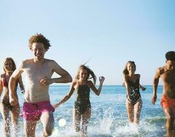 Group of friends run in the sea. Concept of summertime photo