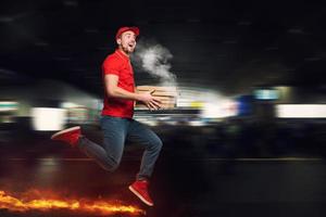 Mensajero en rojo uniforme carreras en pie De Verdad rápido a entregar con rapidez caliente pizzas sólo horneado foto