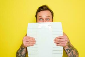 Amazed man with beard and tattoos is hidden behind the scales photo