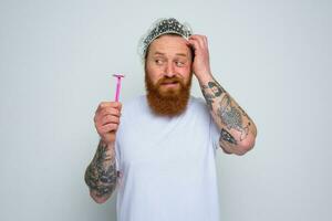 confuso hombre quiere a ajustar el barba con un maquinilla de afeitar espada foto