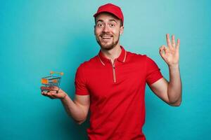 Confident worker with red uniform guarantees on online shopping. Cyan background photo