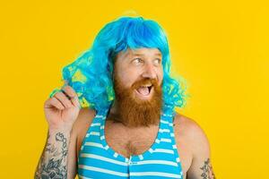 Amazed man with life buoy, swimsuit and blue wig acts like a amazed woman photo