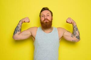 Man with beard and tattoos shows with pride his muscle photo