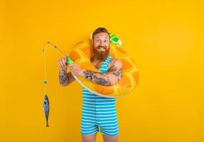 Happy man with beard and inflatable donut catches fish photo