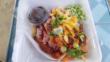 Shrimp paste fried rice with omelette, vegetables and meat in a styrofoam box. photo