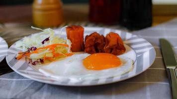 Breakfast, fried eggs, fried sausage, vegetable salad and toast on a brown wooden table with coffee. photo