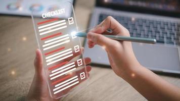Checklist concept, Women check marks on the check boxes with marker red on the futuristic virtual interface screen. photo