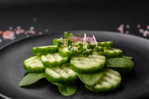 delicioso sano crudo Pepino rebanado en un negro cerámico plato foto