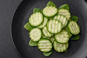 Delicious healthy raw cucumber sliced  on a black ceramic plate photo