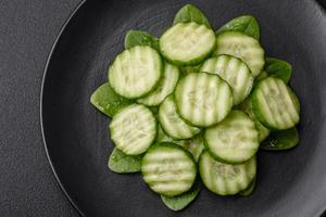 delicioso sano crudo Pepino rebanado en un negro cerámico plato foto